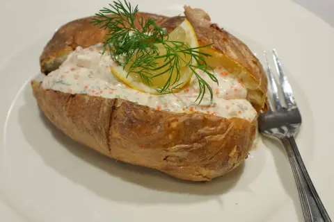 En saftig bakad potatis fylld med en krämig röra med rom, dill och citron. En gaffel ligger bredvid.