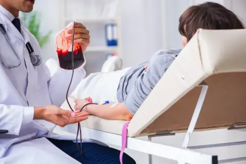 Un médecin prépare une transfusion sanguine pour un patient, une procédure essentielle pour traiter des affections comme la maladie de Biermer.