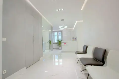 Nowoczesne wnętrze poczekalni kliniki dermatologii estetycznej z recepcją i wygodnymi fotelami.