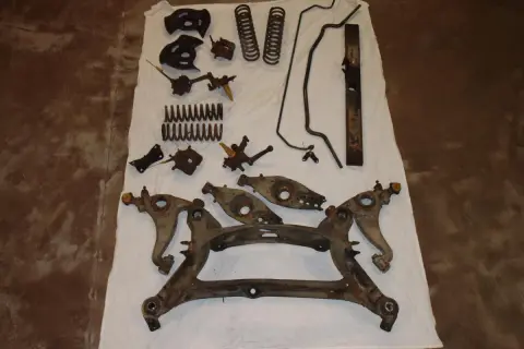 Rostige Autoteile, Federn und Querlenker liegen auf einem weißen Tuch. Die auto sandstrahlen kosten sind hier ein wichtiger Faktor für die Aufbereitung.