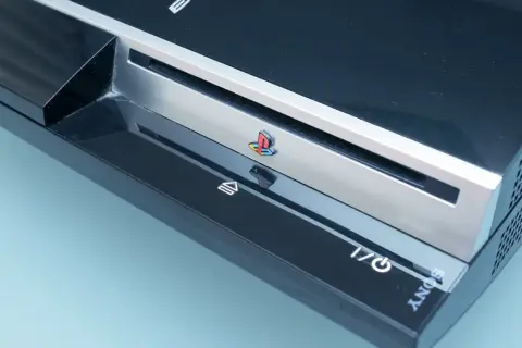 Konsola PlayStation 3, kiedy wyszło PS3, z kolorowym logo PlayStation i przyciskami zasilania i eject.