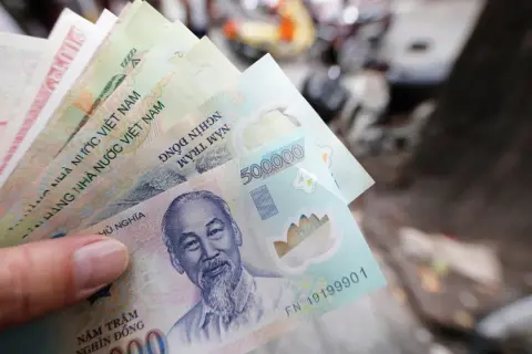 Dłoń trzyma stos banknotów, w tym 500 000 dongów, waluta w Hanoi.