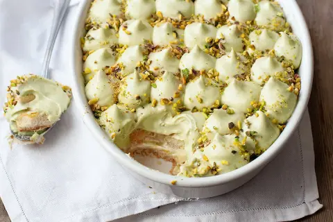 Un cremoso tiramisù al pistacchio, guarnito con granella di pistacchi, pronto per essere gustato.