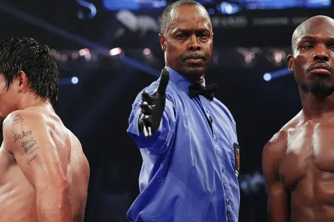 Referee signals between boxers, hinting at a close fight that could end in a majority decision vs split decision.