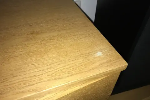 En träyta med tydlig ådring, kanske redo att slipa faner för en jämnare finish. En vit fläck syns på kanten.
