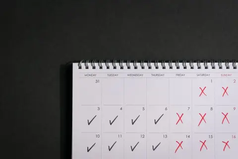 Kalendarz z zaznaczonymi dniami. Czerwone krzyżyki oznaczają dni wolne, a ptaszki dni pracy. To może być plan na urlop rodzicielski 9 tygodni.
