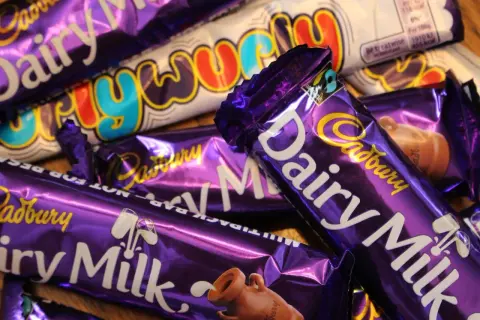 Barras de chocolate Cadbury Dairy Milk y Crunchie, icónicos dulces británicos, apilados en un primer plano.
