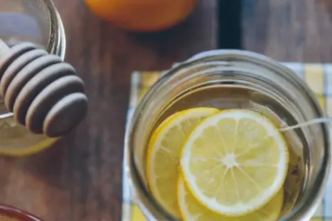Un verre rempli de rondelles de citron, prêt à recevoir du miel et de la cannelle pour ses bienfaits.
