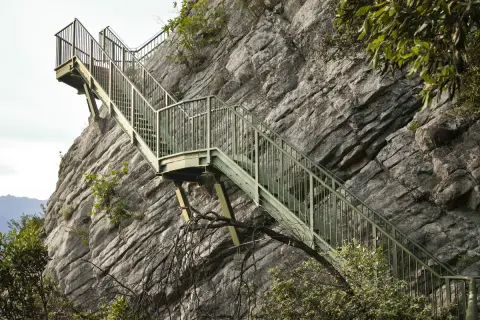 Scalinata metallica aggrappata alla roccia, un sentiero a Torbole che sfida la tempesta.