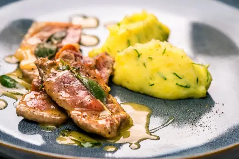 Saltimbocca: Kalbsschnitzel mit Salbei und Schinken, serviert mit Kartoffelpüree. Ein Klassiker, der auf der Zunge zergeht.