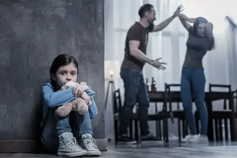 Przerażona dziewczynka tuli misia, podczas gdy rodzice kłócą się w tle. Czy to niebieska karta co to za sytuacja?