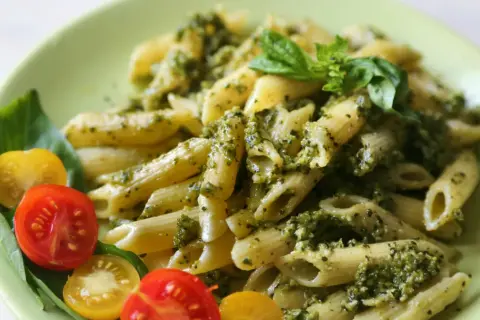 Makaron penne z pesto i świeżą bazylią, podany z pomidorkami koktajlowymi. Idealny sycący obiad bez mięsa.