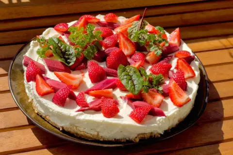 Ein köstlicher Erdbeer Rhabarber Kuchen mit frischen Früchten und Kräutern, bereit zum Genießen.