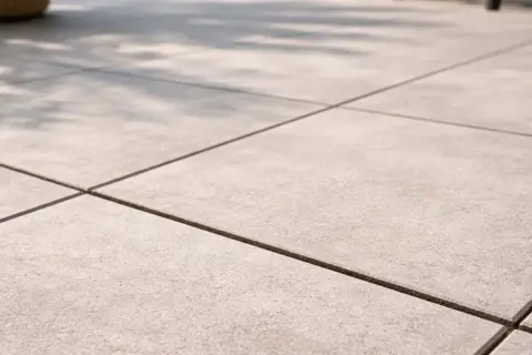 Pavimentazione esterna con piastrelle grigie e fughe scure, perfette per un terrazzo moderno. Il cemento per fughe esterne garantisce durata e stile.