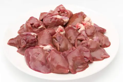 Na białym talerzu ułożona jest świeża, surowa wątróbka dla kota.