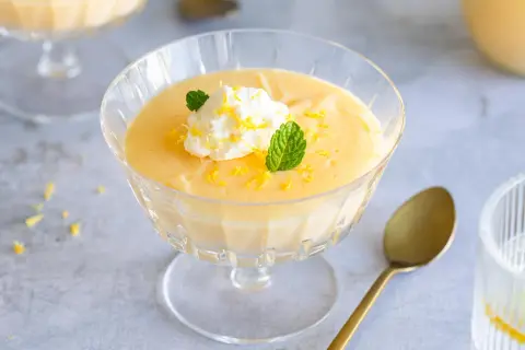 Cremiges Lemon Curd Dessert im Glas, garniert mit Sahne, Minze und Zitronenschale. Perfekt für ein einfaches Lemon Curd Rezept.