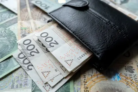 Czarny portfel na stosie polskich banknotów 200 zł. Czy to wystarczy na minimalne wynagrodzenie?
