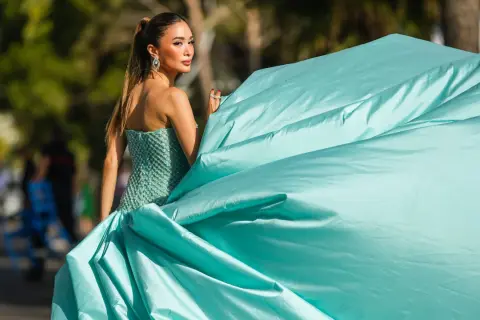 Elegante Dame im mintgrünen Ballkleid, perfekt für einen "black tie optional" Anlass. Ihr Kleid weht im Wind.