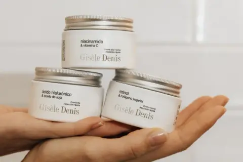 Hände halten drei Gisele Denis Cremetiegel: einer mit Niacinamid & Vitamin C, einer mit Hyaluronsäure & Sojaöl, und einer mit Retinol & pflanzlichem Kollagen.