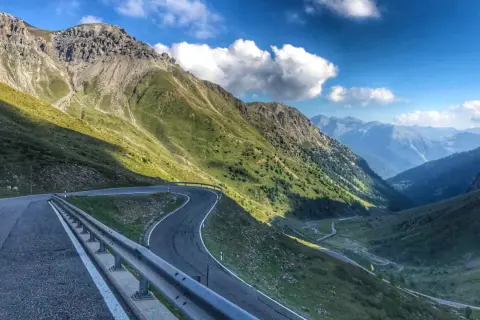 Kręta, górska stelvio droga wije się przez zielone zbocza Alp, prowadząc w głąb doliny.