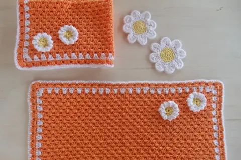 Tovagliette uncinetto schemi gratis: un set arancione con fiori bianchi e gialli, perfetto per decorare la tavola.
