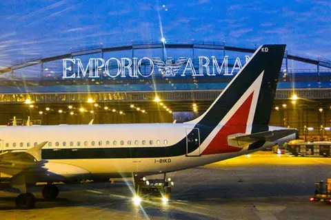 Samolot Alitalia na lotnisku w Mediolanie, w tle podświetlony napis Emporio Armani.