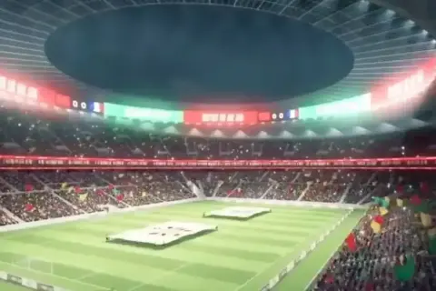 Widok na wypełniony po brzegi stadion, największy stadion na świecie, z flagami i tablicą wyników.