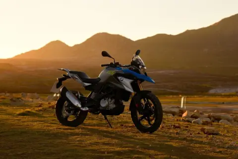 Motocykl BMW GS 310 na tle gór o zachodzie słońca.