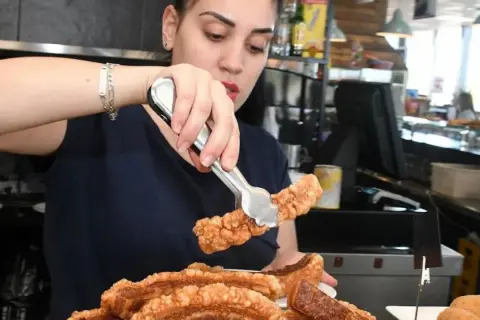 Camarera sirviendo crujiente chicharrón, perfecto para comer en carretera cerca de Zaragoza.