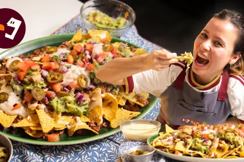 Una mujer disfruta de unos deliciosos nachos tex mex, cargados de carne, guacamole, queso y jalapeños.