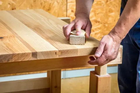 Mains poncent un plan de travail en bois avec une cale à poncer pour une finition lisse.