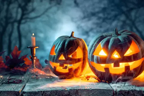 Gruselige Kürbisse mit Kerzenlicht und Herbstlaub. Ein Hauch von Mysterium, das an den Halloween Ursprung in Deutschland erinnert.