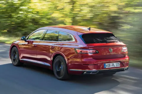 Czerwony Volkswagen Arteon Shooting Brake w ruchu na tle rozmytego krajobrazu.