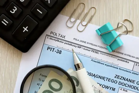 Formularz PIT-38, kalkulator, lupa i pieniądze. Rozliczenie dochodu z art. 27 ust. 9 i 9a ustawy.