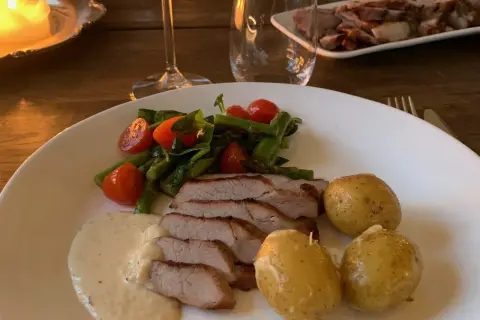 En tallrik med saftigt grillad pluma, serverad med småpotatis, sparris, körsbärstomater och en krämig sås. En härlig måltid!