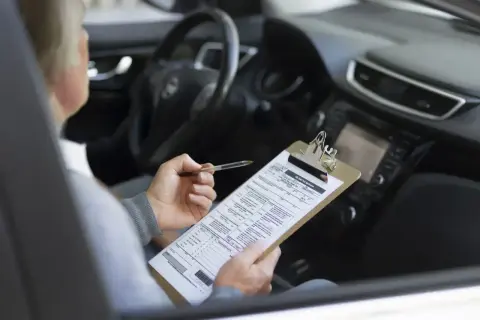 Osoba w samochodzie wypełnia dokumenty dotyczące akcyzy za auto.