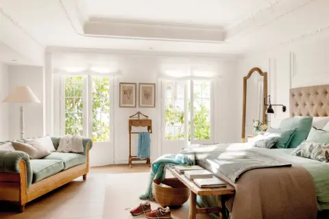 Ideas dormitorio matrimonio: cama con cabecero tapizado, sofá verde, espejo de cuerpo entero y ventanas con luz natural.