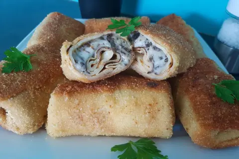 Chrupiące krokiety z pieczarkami i serem, jeden przekrojony, ukazujący bogate wnętrze.