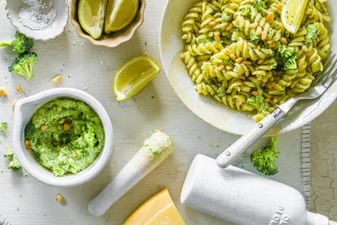 Frische Pasta mit cremigem Brokkoli Pesto, Pinienkernen und Zitrone. Zutaten für das Pesto sind sichtbar.