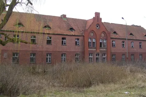 Opuszczony budynek z cegły, zniszczony dach i wybite okna. Miejsce to mogłoby być jednym z nawiedzonych miejsc w Polsce, budzącym grozę.