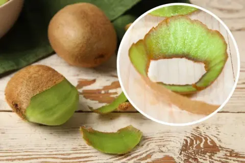 Kiwi ze skórką, częściowo obrane, leżą na drewnianym blacie. W okręgu widać zieloną skórkę kiwi.