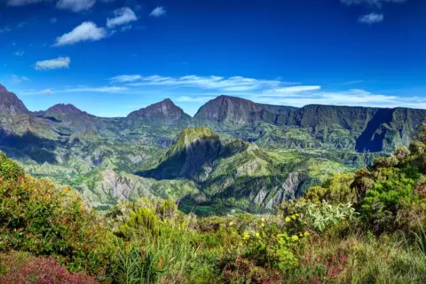 Paysage montagneux verdoyant sous un ciel bleu. Idéal pour réfléchir à que faire à la Réunion.