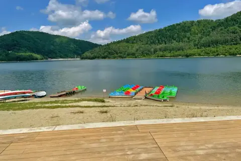 Kolorowe rowerki wodne i kajaki czekają nad spokojnym jeziorem w górach.