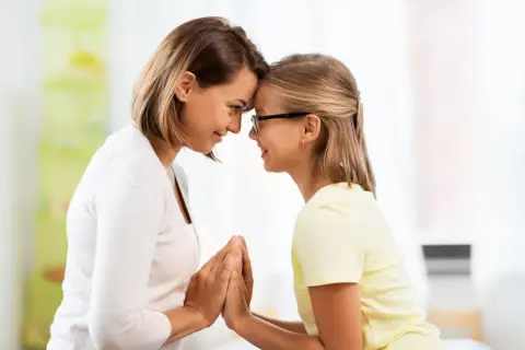 Madre e figlia si guardano con affetto, le fronti unite. Un momento di connessione profonda, che a volte può nascondere la psicologia di una madre invidiosa della figlia.