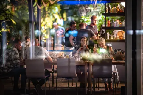 Ludzie siedzą przy stole w restauracji Olivia Business Centre, pijąc i rozmawiając.