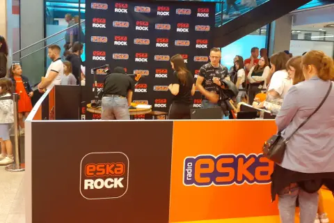 Stoisko radiowe Eska Rock z ludźmi i logo stacji.