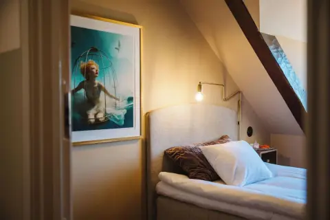 En konstnärlig tavla med en kvinna i en bur under vatten pryder väggen i ett mysigt rum på hotellet Höganäs.