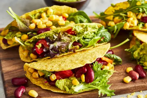Knusprige, vegetarische Tacos gefüllt mit Guacamole, Kidneybohnen, Mais, Tomaten und Salat. Ein bunter Genuss!