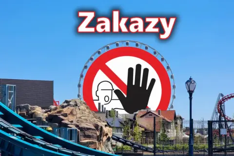 Znak zakazu na tle parku rozrywki Energylandia z diabelskim młynem i kolejką górską.