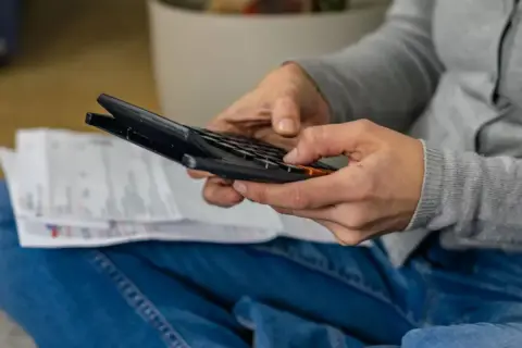 Osoba liczy rachunki, sprawdzając, czy taryfa nocna Energa jest opłacalna.